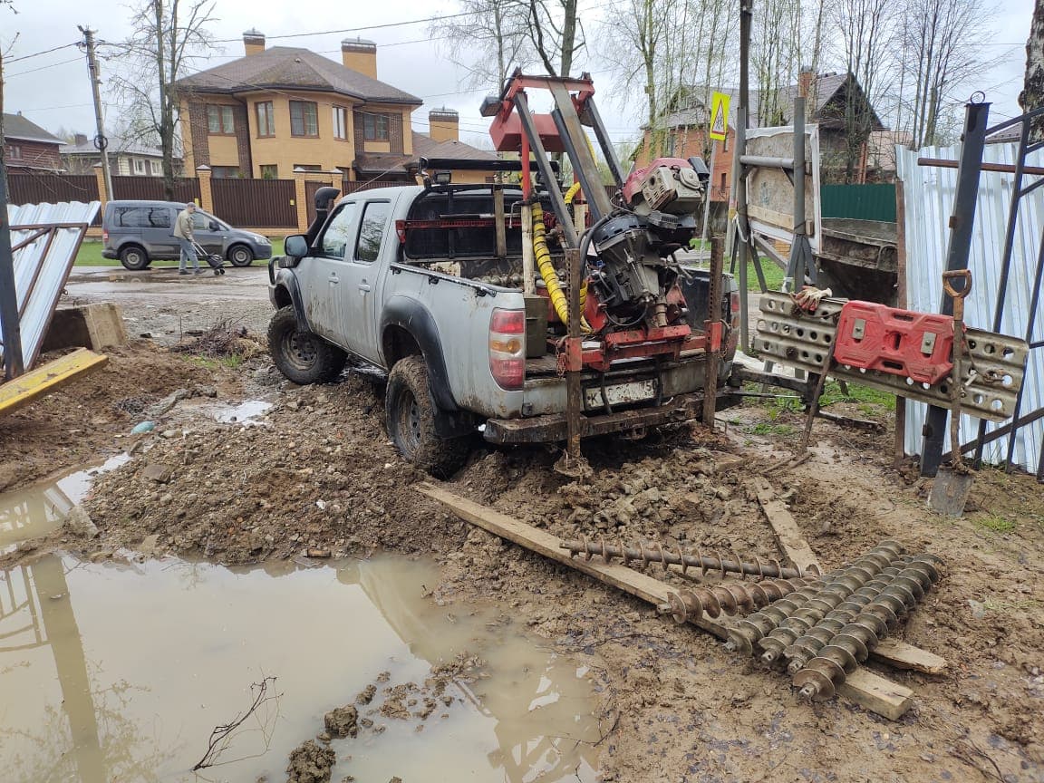 Компактная буровая установка работает на участке рядом с загородным домом